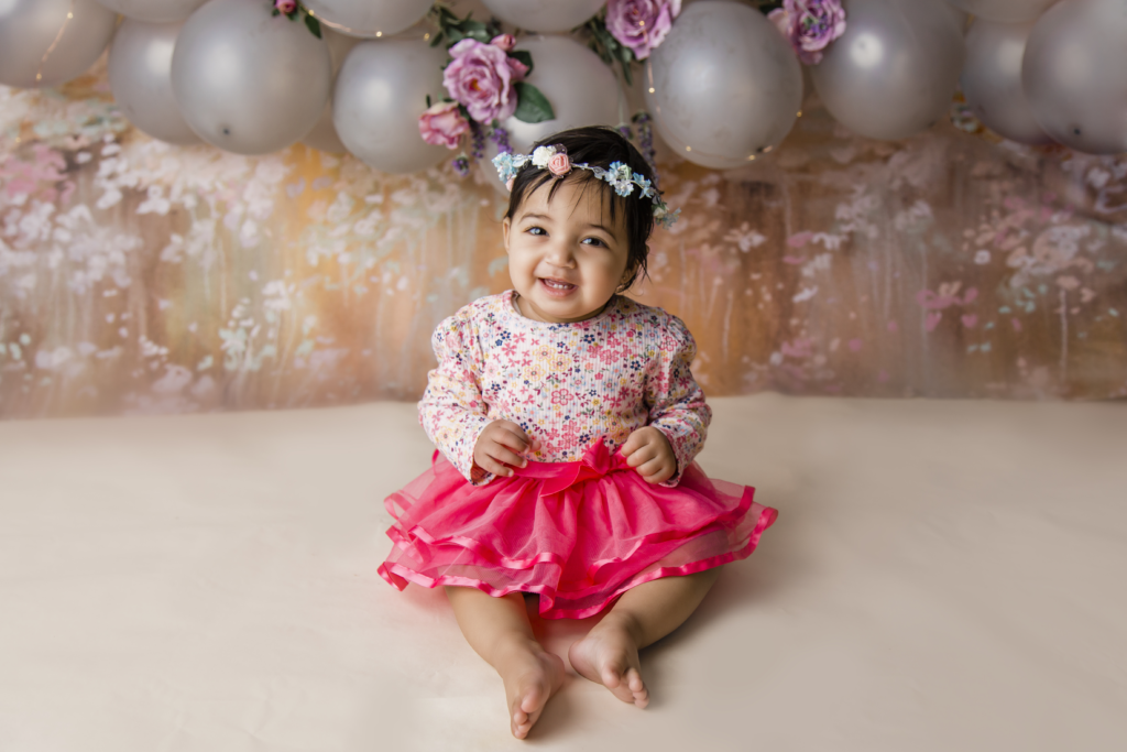 Robina, QLD Cake Smash Photographer infant in pink tutu, balloon arch, floral backdrop